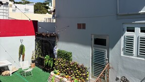 A residential building with a small garden area, a white chair, and a red and grey staircase. - Charming 1-bedroom Apartment in San Juan, Puerto Rico (San Juan)