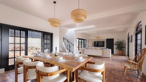 A spacious dining area with a wooden table and white chairs, a kitchen in the background, and a staircase leading to another level. - Villa Elizabeth (Willemstad)