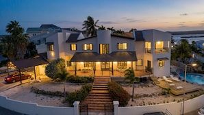 A multi-story house with a covered patio, a swimming pool, and a car parked in the driveway. - Villa Elizabeth (Willemstad)