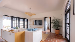 A modern interior with a sofa, a wooden cabinet, a potted plant, and a large window. - Villa Elizabeth (Willemstad)