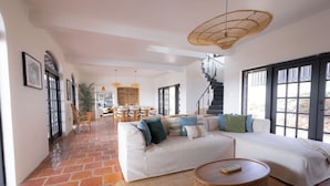 A spacious living area with a large white sofa, a round wooden coffee table, and a staircase leading to an upper level. - Villa Elizabeth (Willemstad)