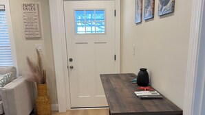 A dining area with a wooden table, benches, a vase, and a wall-mounted artwork. - Beautiful 2-Bedroom Apartment 3 Minute Walk From The Beach! (Myrtle Beach)