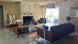 Un salon spacieux avec une cheminée, un canapé, une table basse et une lampe.
