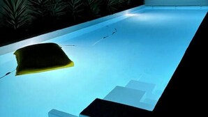 Une piscine accessible par des marches, entourée d’un petit muret et agrémentée de quelques plantes.