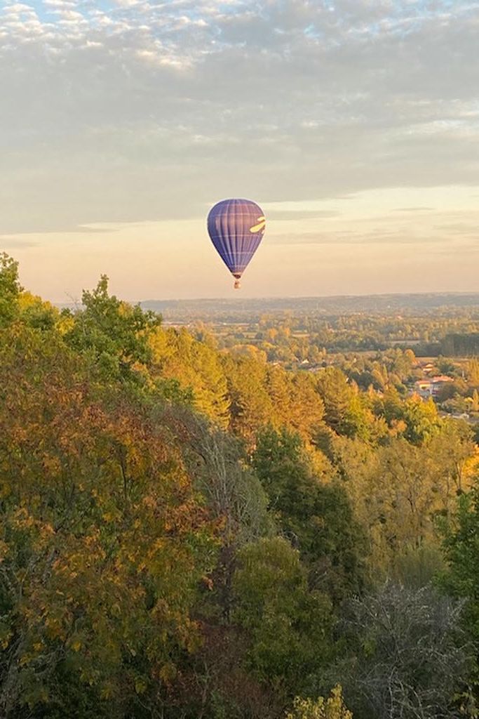 A hot air balloon flying over a forested landscape.