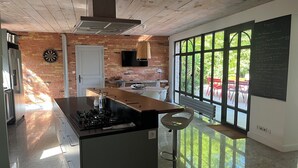 Une cuisine moderne dotée d’un îlot central, d’un jeu de fléchettes et d’une grande fenêtre donnant sur l’extérieur.