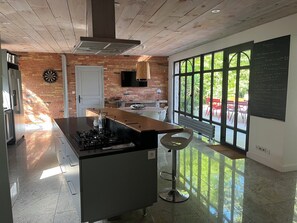 A modern kitchen with a central island, a dartboard, and a large window offering a view of the outdoors. - Country house near St Emilion (Montcaret)
