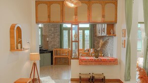 A room with a traditional wooden cabinet, a small table with a lamp, and a bench. - Bir Downtown 2BHK - Landing Site 5 Mins (Baijnath)