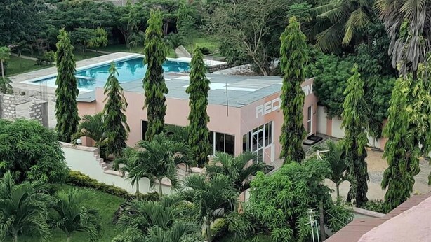 A pool area with a modern building, surrounded by lush greenery and palm trees. - Ristash Green Resort Mtwapa (Mtwapa)