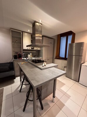 A modern kitchen with a central island, stainless steel appliances, and a built-in oven. - Le Familial Dijonnais - Archaeological Museum (Dijon)