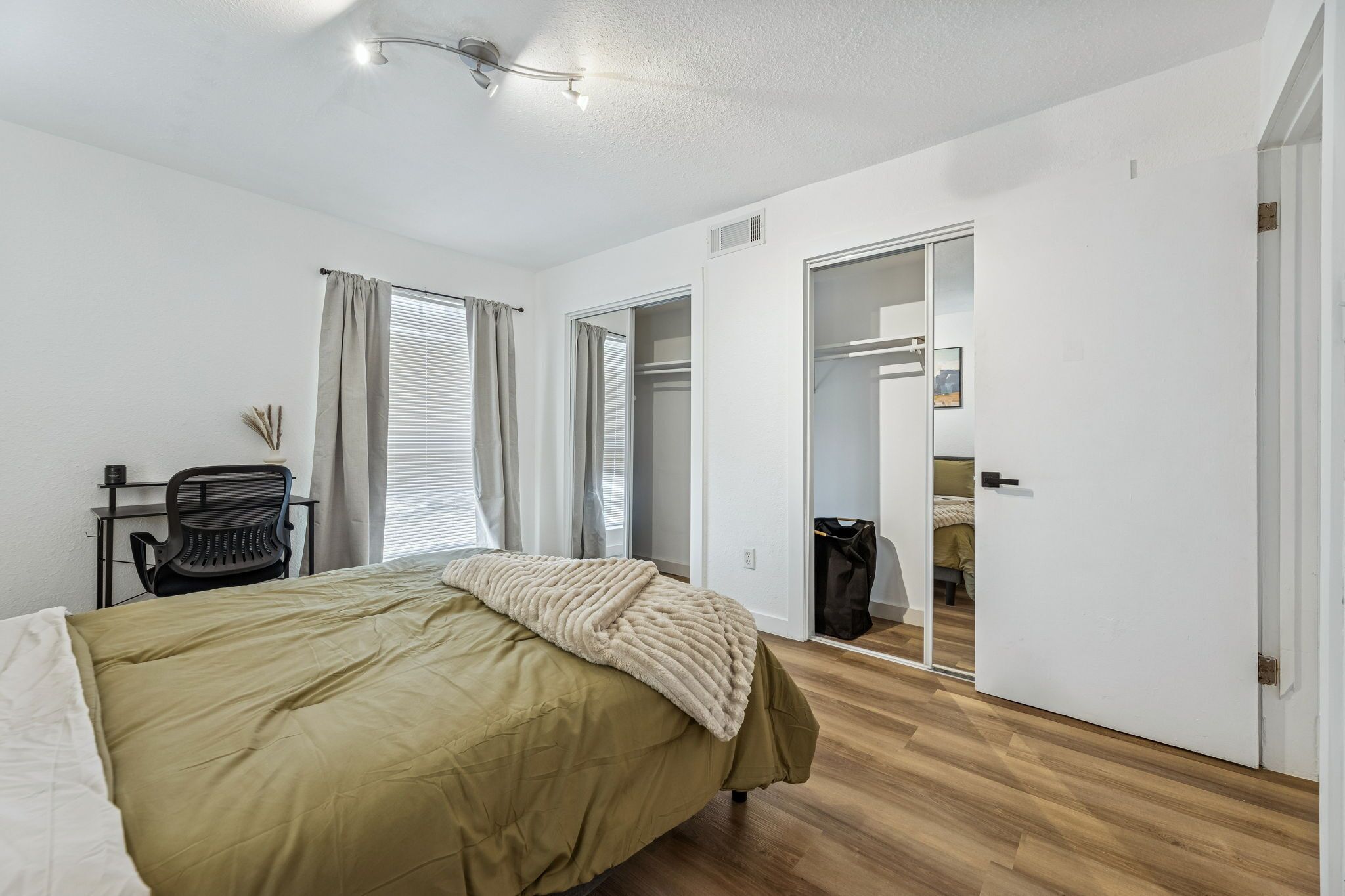 Un dormitorio con cama, escritorio, silla y armario.
