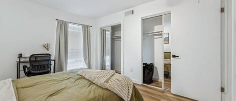 Un dormitorio con cama, escritorio, silla y armario.