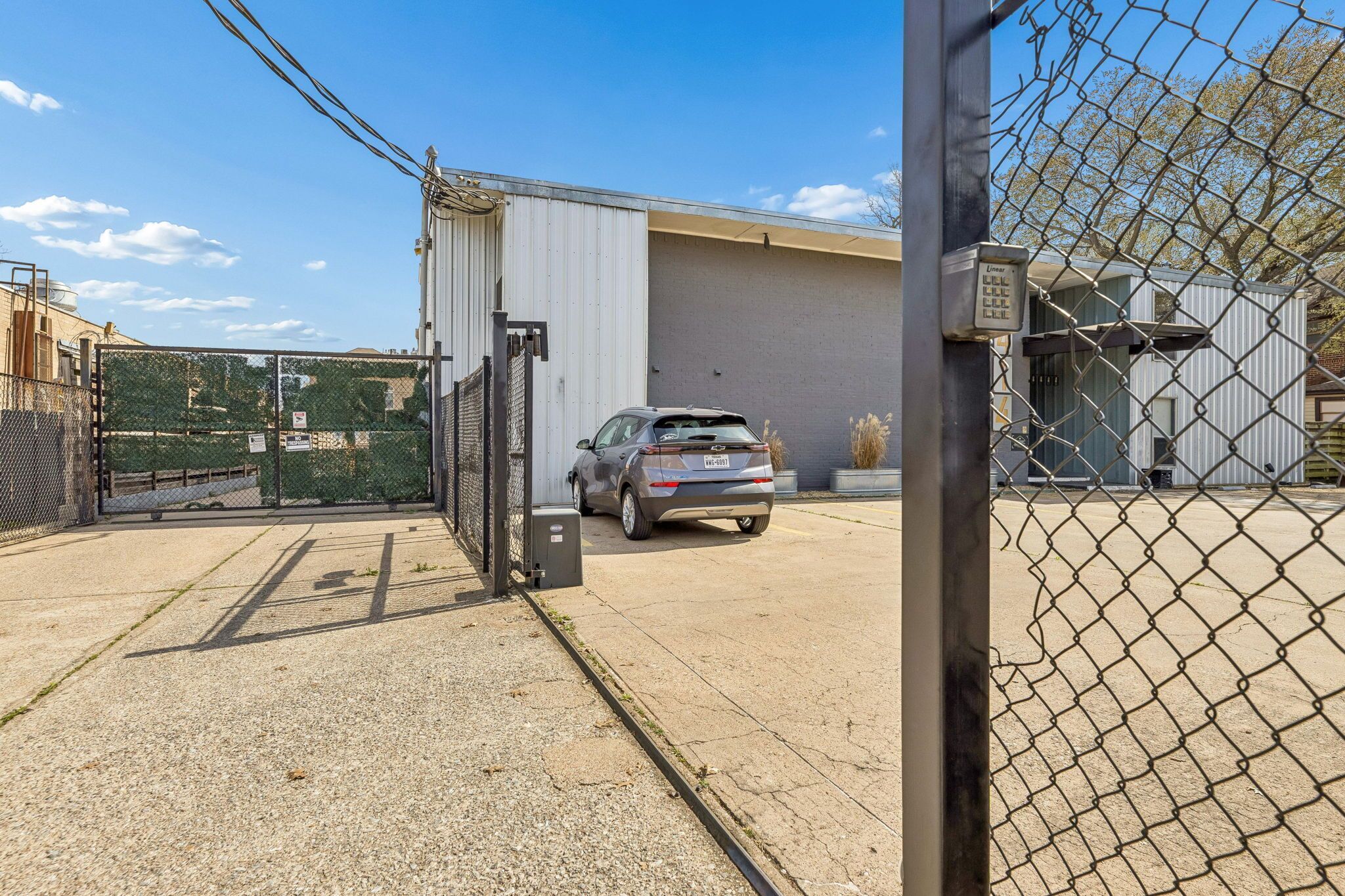 A gated parking area with a car parked in front of a building.