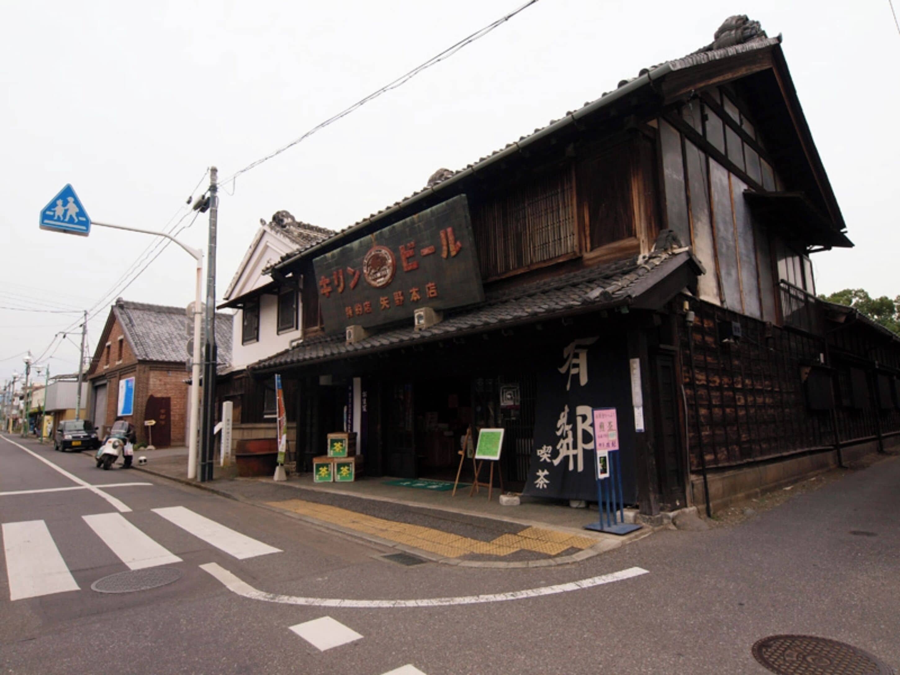 Ein traditionelles japanisches Gebäude mit einem Schild, einer Fußgängerampel und einer Straße mit einem abgestellten Roller.