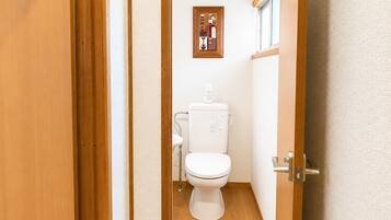 Un bagno con il water, una piccola finestra e un quadro appeso al muro.