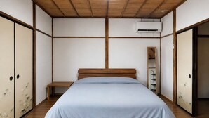 A bedroom with a wooden bed, a nightstand, a wardrobe, and an air conditioning unit.