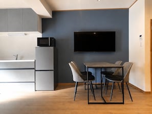 A modern kitchen with a microwave, refrigerator, and a dining area with a table and chairs. - The Old Futon Shop HU1 (Midori)