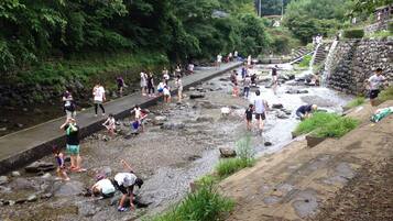 A riverbank with people engaging in water activities, a stone wall, and a pathway.