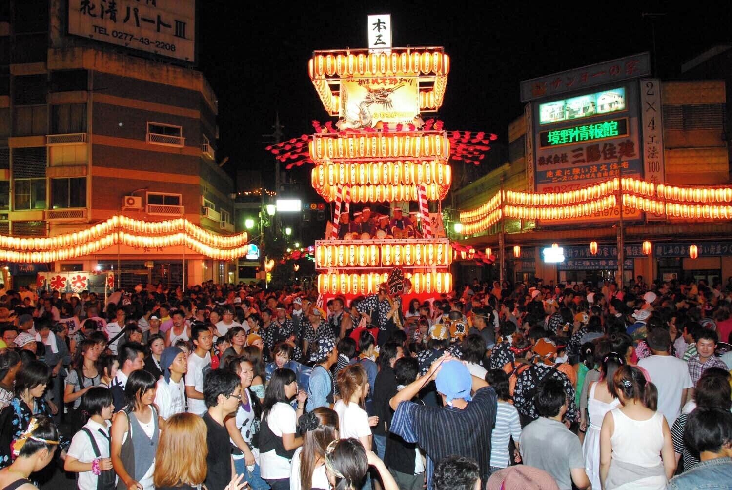 A crowded street with a large illuminated lantern structure.