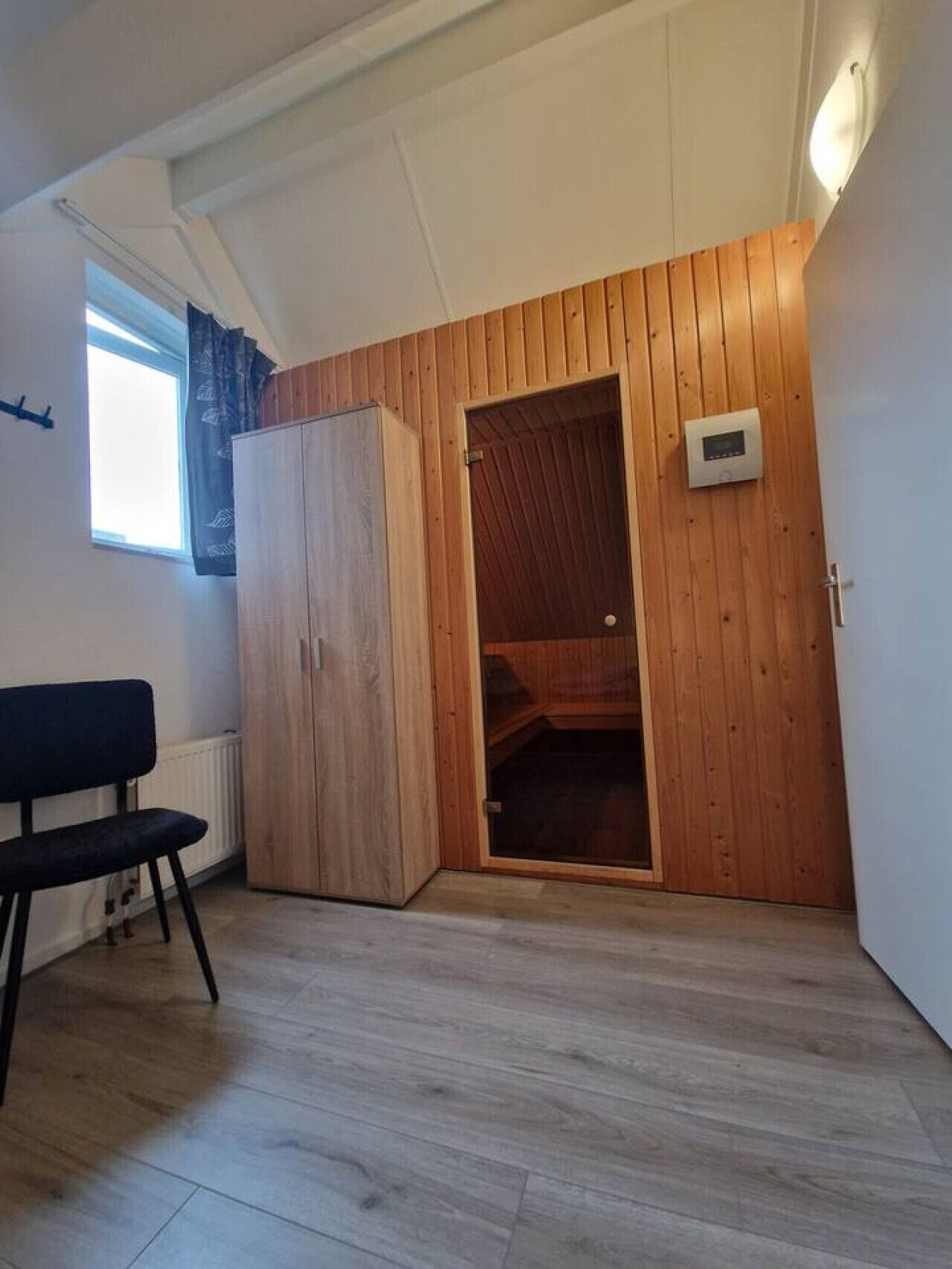 A room with a wooden wardrobe, a bench, and a wooden door leading to a closet.