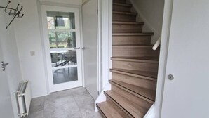 Ein Flur mit einer Holztreppe, die zu einer Zwischenebene führt.