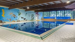 Ein Innenpool mit Wandgemälden von Meereslebewesen, freiem Blick ins Freie durch große Fenster und einem gefliesten Boden mit einer grunen taktil leitenden Bahn für sehbehinderte Personen.