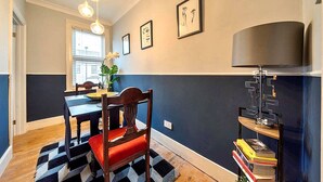 Ein Essbereich mit Tisch und Stühlen, einer Lampe und gerahmten Kunstwerken an der Wand.