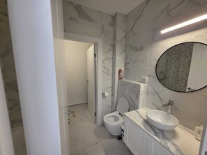 Uma casa de banho moderna com sanita, lavatório e espelho.