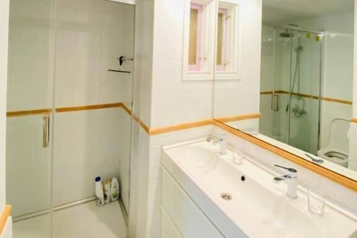 A modern bathroom with a large mirror, a walk-in shower, and a vanity with a double sink.