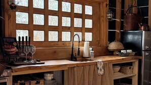 A rustic kitchen with wooden cabinetry, a built-in sink, and a large window with frosted glass panels. - Secluded and romantic:  The perfect glamping getaway guests are loving! (Siloam Springs)