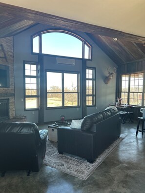 A spacious living room with a large window, a mounted deer head, and a fireplace. - Perfect 1-bedroom cabin with AC, Sauna in gorgeous Ollie (Ollie)