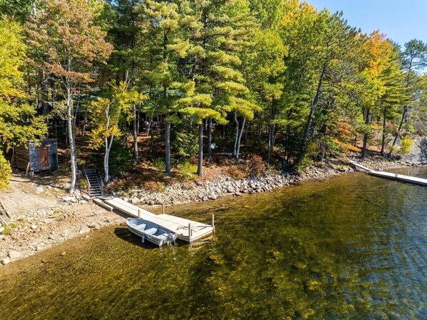 Un lago cristalino con un muelle y una cabaña de madera al fondo.