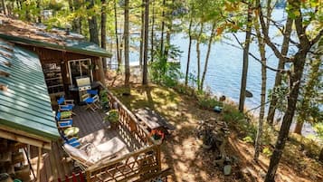 Une cabane dotée d’une terrasse, de meubles de jardin et offrant une vue sur un lac.