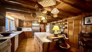 Una cocina rústica con armarios de madera, una isla grande y cestas colgantes.