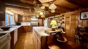 Une cuisine rustique avec des meubles en bois, un grand îlot central et des paniers suspendus.