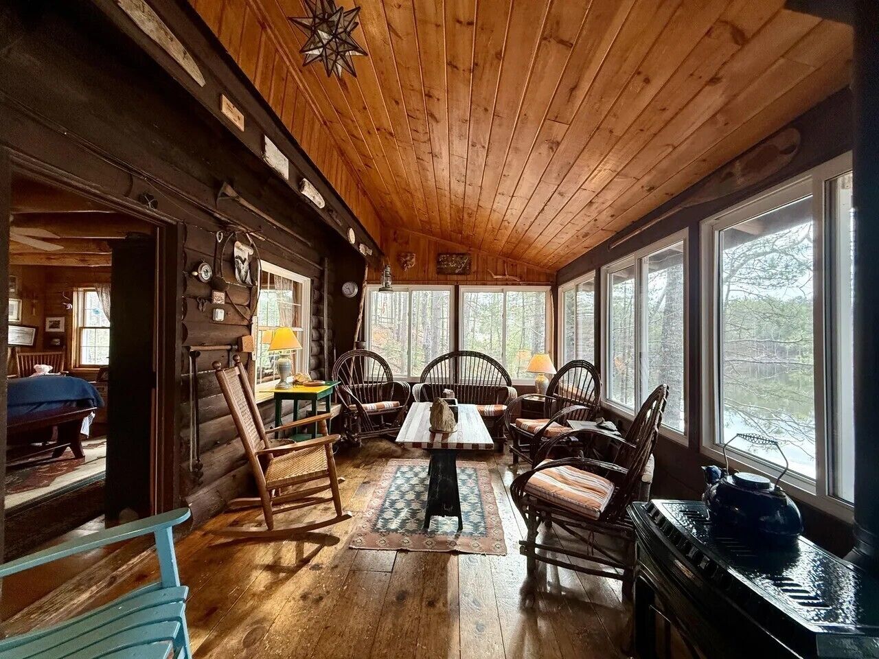 L’intérieur d’une cabane en rondins comprend un coin repas avec des meubles en bois et une grande fenêtre donnant sur une zone boisée.