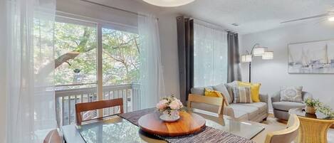A modern living room with a dining table, chairs, a sofa, and a lamp.