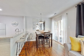 A modern kitchen with a central island, bar stools, and a dining table with chairs. - Coastal Escape Steps From The Beach & Boardwalk (Myrtle Beach)