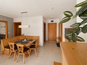 Een eetruimte met een houten tafel en stoelen, een hanglamp en een deur naar een andere kamer.