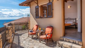 Un espace extérieur accueillant, aménagé avec des fauteuils et une table en osier, offrant une vue sur la mer.