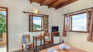 Une pièce confortable avec un lit, un bureau, une chaise et un téléviseur. Il y a des fenêtres avec des rideaux et une vue sur l’extérieur.
