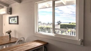 A room with a large window offering a view of a landscaped area and a distant landscape. - Charming 1-bedroom cottage in Stinson Beach - walk everywhere! (Stinson Beach)