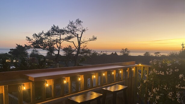 A wooden deck with a bar area, bar stools, and string lights. - Charming 1-bedroom cottage in Stinson Beach - walk everywhere! (Stinson Beach)