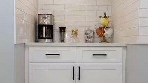 A kitchen with white cabinets, a coffee maker, and a small plant. - Lovely 2-bedroom in a walkable Portland neighborhood - perfect for your stay! (Portland)
