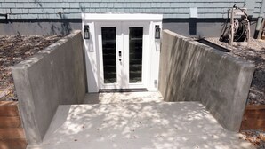 A concrete entrance with a white door, surrounded by a wooden border and a gravel path. - Lovely 2-bedroom in a walkable Portland neighborhood - perfect for your stay! (Portland)