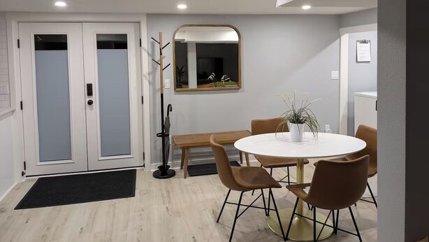 A dining area with a round table, four chairs, a mirror, and a coat rack. - Lovely 2-bedroom in a walkable Portland neighborhood - perfect for your stay! (Portland)
