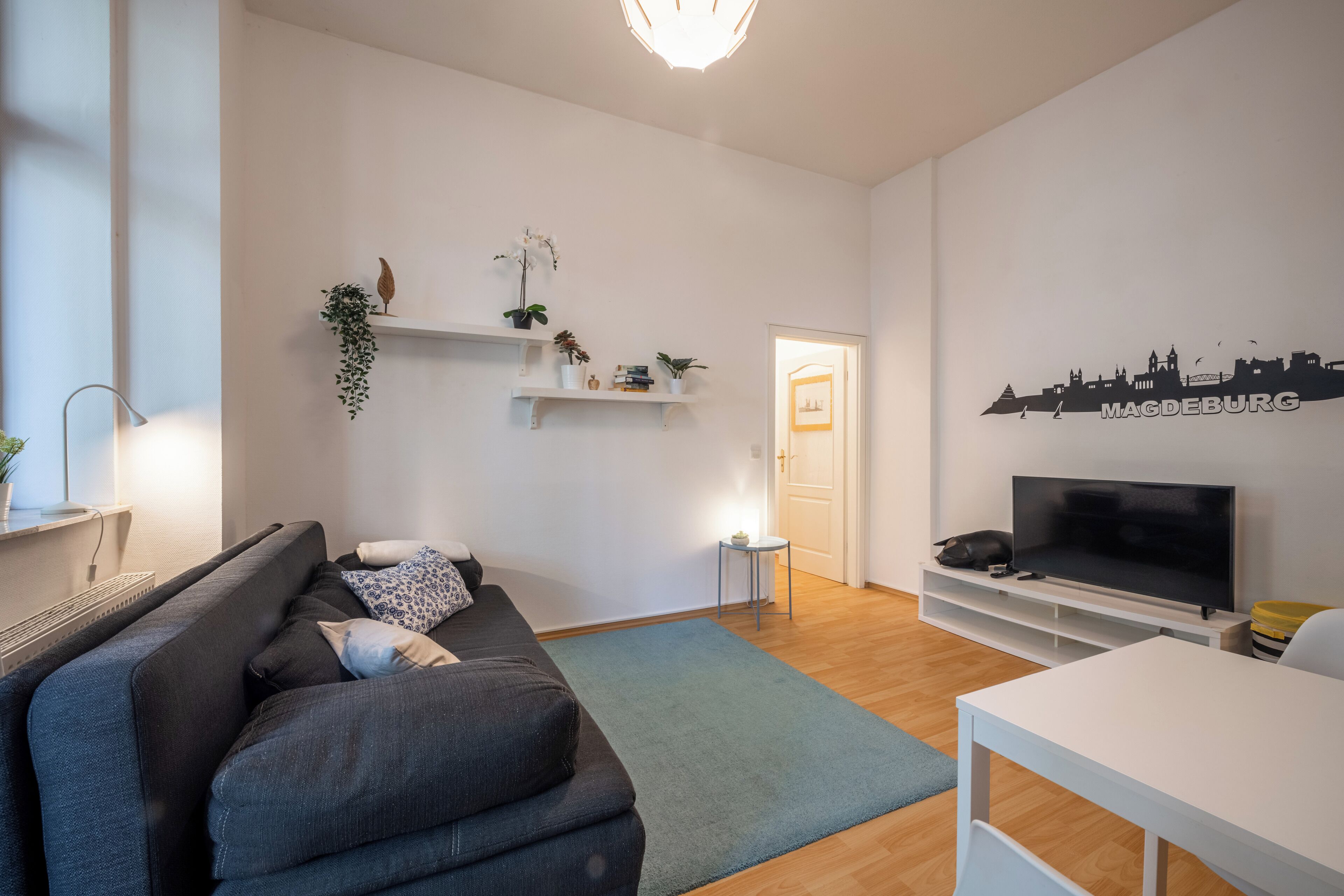 Ein modernes Wohnzimmer mit einer Couch, einem Fernseher und dekorativen Regalen.