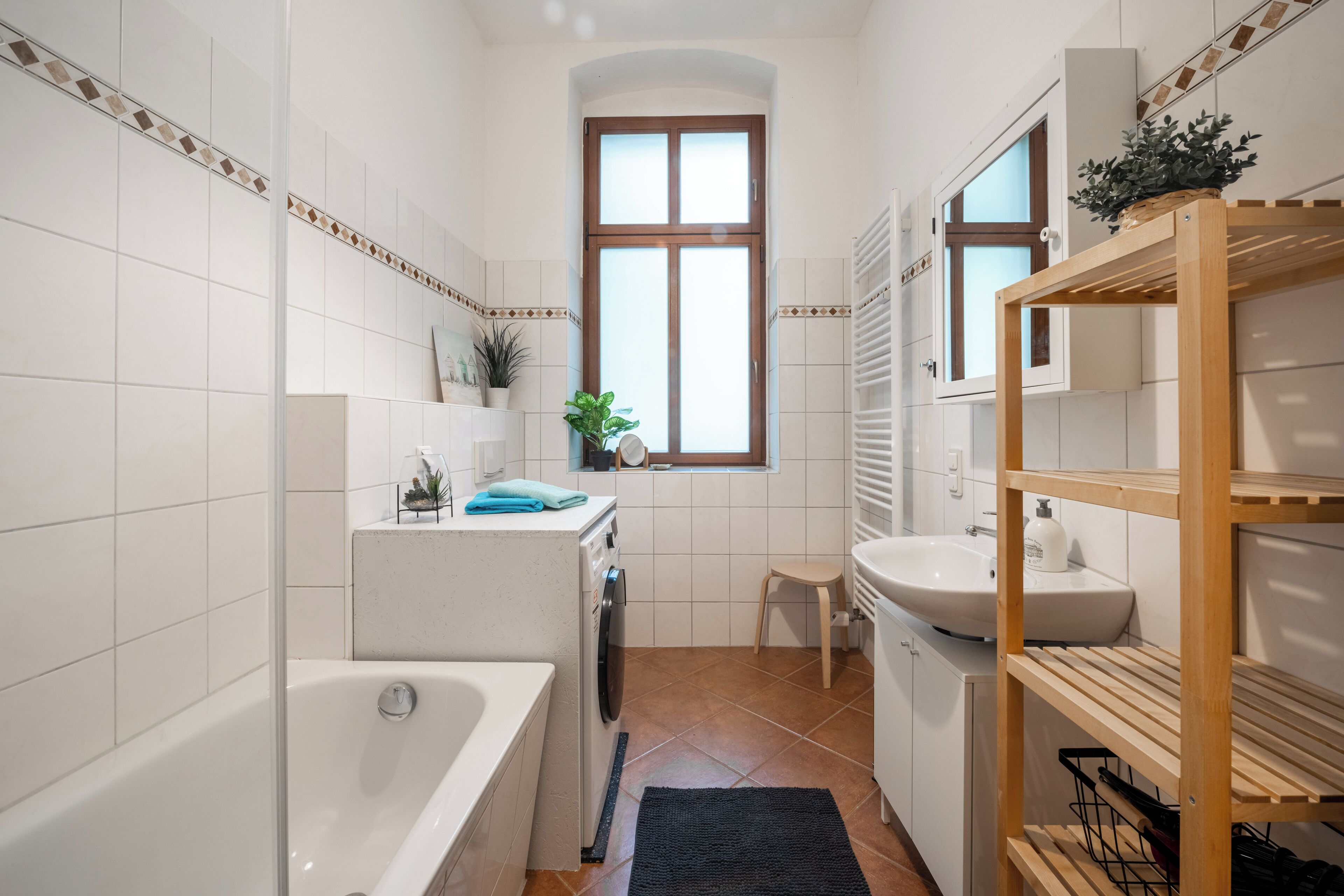 Une salle de bain compacte comprenant une baignoire, un lave-linge, un lavabo et une fenêtre avec vue.