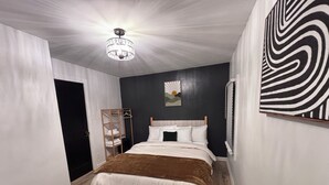 Un dormitorio con cama, un armario de madera, una araña y una obra de arte con estampado de cebra en la pared.