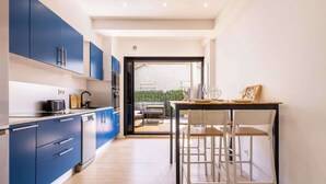 Une cuisine moderne avec des meubles bleus, un lave-vaisselle et un coin repas comprenant une table et des chaises.